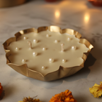 Decorative candle in a gold holder with small candles and flowers on a marble surface